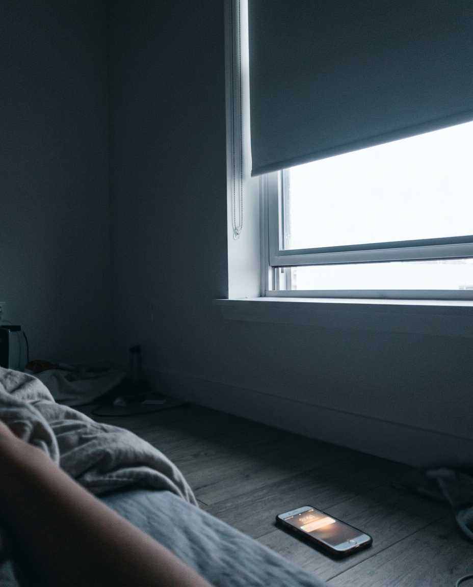 Grey early light coming through a bedroom window with the blind half up