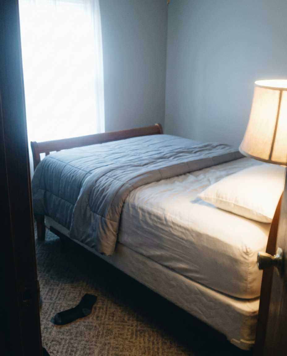 A made bed in early morning light, nobody in the room